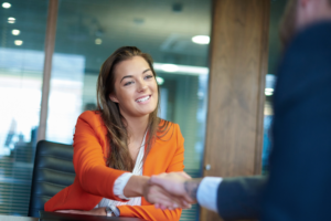 Business woman shaking hands with business man in an interview setting across a conference room table