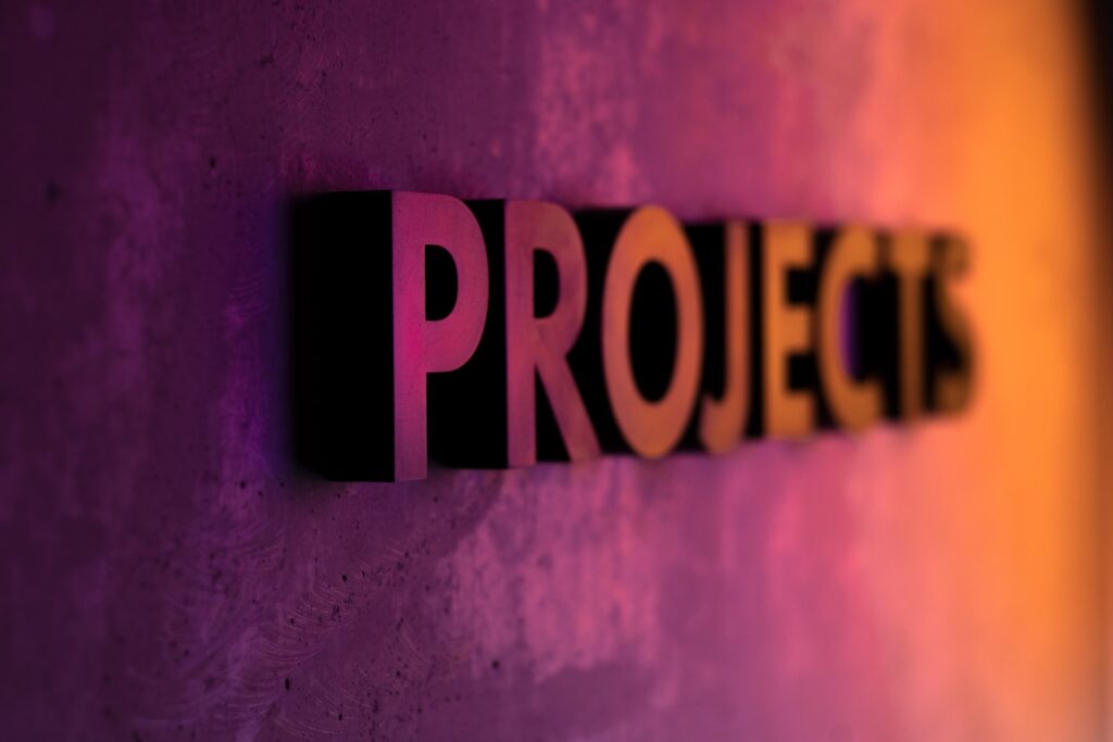 A dramatic, 3D word "Projects" stands out on a wall that is pink and ombres to orange.