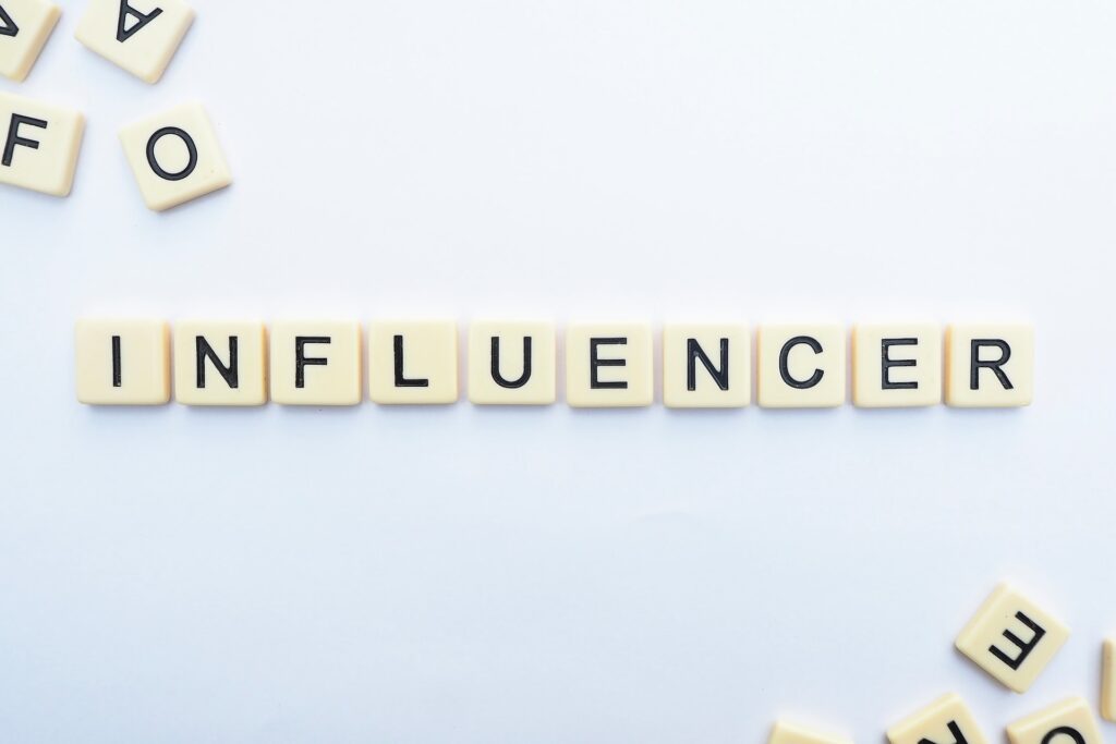 A white background with scrabble tiles. A handful of tiles are arranged to spell "influencer."